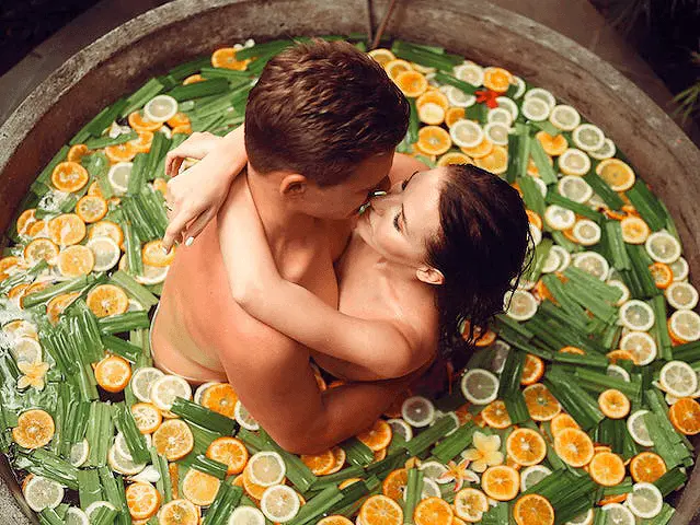 How Sex Makes You Lose Weight Image of a Man and Woman Kissing in a Hot Tub full of orange and lime slices with green leaves