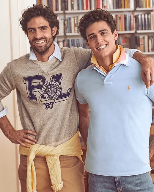 Two preppy male fashion models smiling wearing popped polo collar shirts with their arms around each other