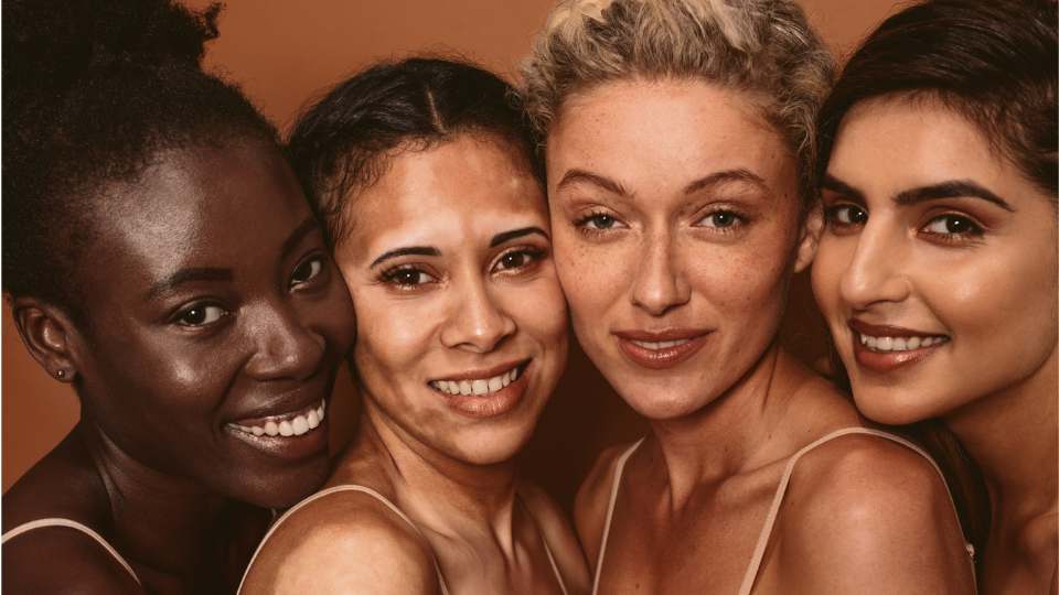 Faces of four multirace women standing together smiling